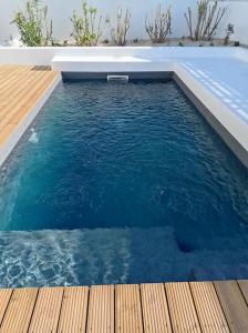 a pool of blue water with a wooden deck at Casa Monda- Comporta in Carvalhal