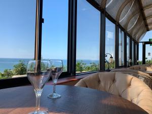 two wine glasses sitting on a table with a view of the ocean at Tyr Graig Castle in Barmouth