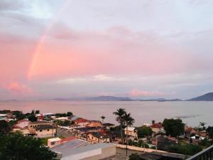un arco iris en el cielo sobre una ciudad y el agua en Apto Beira Mar Grande Floripa, en Palhoça