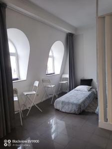 a bedroom with two windows and a bed and chairs at Oporto apartment Batalha in Porto
