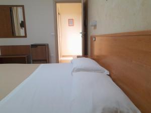 1 dormitorio con cama blanca y cabecero de madera en B&B Il Giardino di Zefiro, en Gioiosa Marea