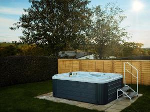 a hot tub sitting in a yard next to a fence at Tor Cottage in Exeter