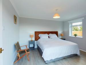 um quarto com uma cama, uma cadeira e uma janela em Tor Cottage em Exeter