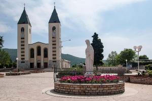 a statue in front of a church with two towers at Didovina House in Vodenjak