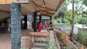 dos personas sentadas en bancos bajo un porche en Delta Island Camping Ground en Sumedang