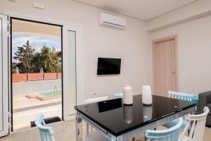 a dining room with a table and chairs and a television at Astarte Villas - Coral Bleu Villa with Private Pool in Tsilivi
