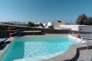 - une piscine d'eau bleue dans la cour dans l'établissement Aspa Villas, à Oia