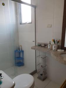 y baño blanco con aseo y ducha. en Apartamento em Guarapari, en Guarapari