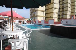 ビージャ・ヘセルにあるHosteria San Marcosの白いテーブルと椅子と傘のあるプール