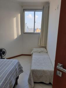 a small room with two beds and a window at Apartamento em Guarapari in Guarapari