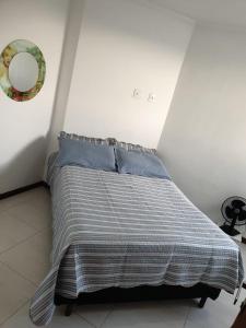 1 dormitorio con 1 cama con colcha a rayas en Apartamento em Guarapari, en Guarapari
