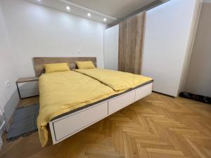 um quarto com uma cama grande e um cobertor amarelo em Mici's Apartments em Visoko