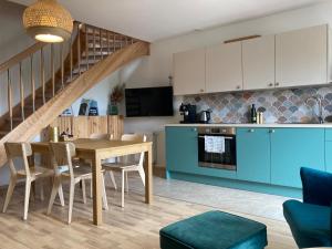 a kitchen and dining room with a table and blue cabinets at Uroczy Apartament u Mirki in Podgórzyn