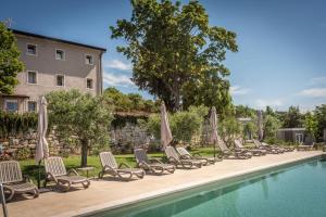 eine Reihe von Stühlen und Sonnenschirmen neben einem Pool in der Unterkunft Il Biotto in SantʼAmbrogio di Valpolicella