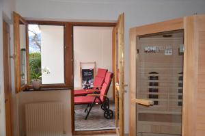 einem roten Stuhl auf einem Balkon vor einer Tür in der Unterkunft Apart Franziska in Kauns