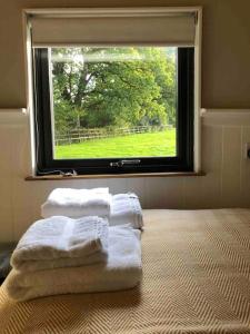 a group of towels sitting on a bed in front of a window at Aspen Leaves: The perfect farm retreat in Graffham