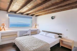 a bedroom with a bed and a large window at Villa Phaedra by Whitelist Mykonos in Agios Ioannis Mykonos