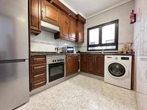 a kitchen with wooden cabinets and a washer and dryer at apartment arrecife beyond in Arrecife