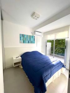 Un dormitorio con una cama azul y una ventana en Departamento a estrenar con pileta y gimnasio en Buenos Aires
