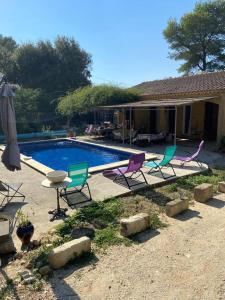 um grupo de cadeiras e uma mesa ao lado de uma piscina em Villa piscine et climatisation em Sauveterre