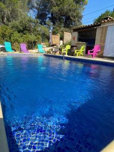 uma grande piscina com cadeiras coloridas num quintal em Villa piscine et climatisation em Sauveterre