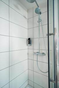 a shower in a bathroom with white tiles at Hotel Scharfes Eck in Mühlacker