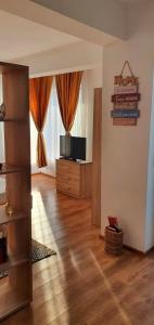 een woonkamer met een televisie en een houten vloer bij Studio Harmony Techirghiol in Techirghiol