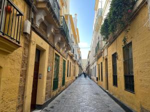 un vicolo vuoto in una città con edifici gialli di Patiovecino Apartment Centro de Cádiz a estrenar a Cadice