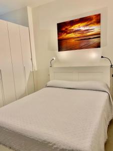 una camera da letto con un letto bianco e un dipinto sul muro di NOVELLA DEL MAR prima fila dal mare a Grottammare