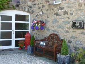 a wooden bench sitting in front of a stone building at Yr Hen Felin - The Old Mill B&B in Morfa Nefyn