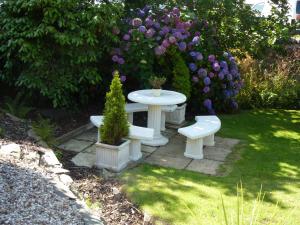 a white table and benches in a garden with flowers at Yr Hen Felin - The Old Mill B&B in Morfa Nefyn