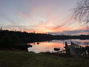 un coucher de soleil sur un lac avec un pont en bois dans l'établissement Kvarnsjöns Naturcamping, à Sjötofta