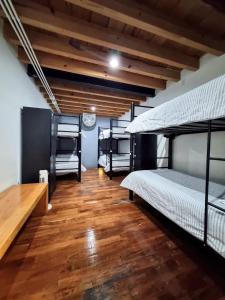 Habitación con 3 camas y suelo de madera. en Metro Hostal Boutique en Ciudad de México