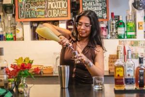 Waikiki Hostel في ليما: امرأة تقف وراء منضدة تقدم الشراب