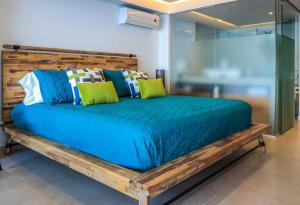 ein großes Holzbett mit grünen und blauen Kissen in der Unterkunft 2bdr, Beach front Luxury Sunset view Heated Pools /Gym in Puerto Vallarta