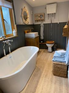 a bathroom with a tub and a sink and a toilet at The Nutshell. Rural retreat in Pluckley