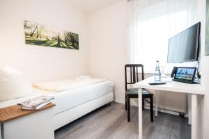 1 dormitorio con 1 cama y escritorio con ordenador portátil en Hotel Scharfes Eck, en Mühlacker