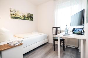 a bedroom with a bed and a desk with a laptop at Hotel Scharfes Eck in Mühlacker