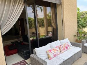 un sofá blanco con 2 almohadas en el patio en Marrakech le joyau Big villa piscine privée jardin, en Marrakech