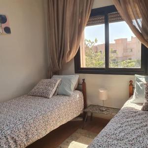 1 dormitorio con 2 camas y ventana en Marrakech le joyau Big villa piscine privée jardin, en Marrakech