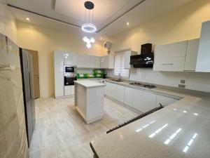 a large kitchen with white cabinets and appliances at Exquisite 5 Bedroom Villa in Kano in Kano