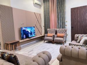 a living room with a couch and a tv and chairs at Exquisite 5 Bedroom Villa in Kano in Kano