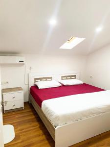 a bedroom with a large white bed with red sheets at Guest House Himaj in Berat