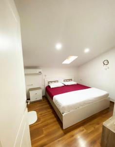 een slaapkamer met een groot wit bed met rode lakens bij Guest House Himaj in Berat