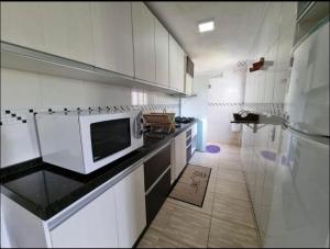 cocina con armarios blancos y microondas en la encimera en APARTAMENTO BC, en Balneário Camboriú