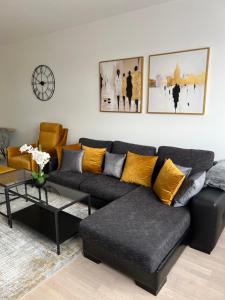 uma sala de estar com um sofá preto e almofadas amarelas em Luxury Apartment Kadic em Sarajevo