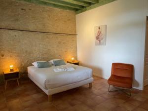 ein Schlafzimmer mit einem Bett und einem Stuhl in der Unterkunft LAURAGUEL CHAMBRES D'HÔTES in Mourvilles-Hautes