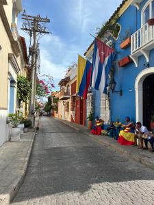 a street with people sitting on the side of a blue building at Loft en Casa Colonial del Centro Histórico de Cartagena in Cartagena de Indias