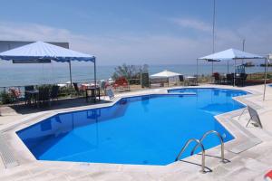 una grande piscina blu con tavoli e ombrelloni di Helena's Dream Home, Glyfada Corfu no7 a Glifada (Glyfada)