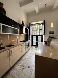 a large kitchen with white cabinets and a sink at Loft en Casa Colonial del Centro Histórico de Cartagena in Cartagena de Indias